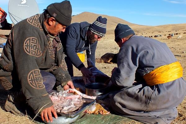 Un volontaire de Projects Abroad aide deux habitants locaux à préparer un repas à l’extérieur dans le cadre du projet nomade en Mongolie Voyager autrement en participant à notre projet en culture et communauté