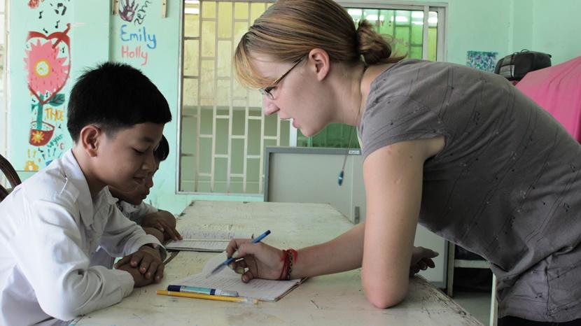 Volontaire avec un enfant dans le cadre de notre projet en enseignement au Cambodge, en Asie Une volontaire enseigne à un enfant au Cambodge