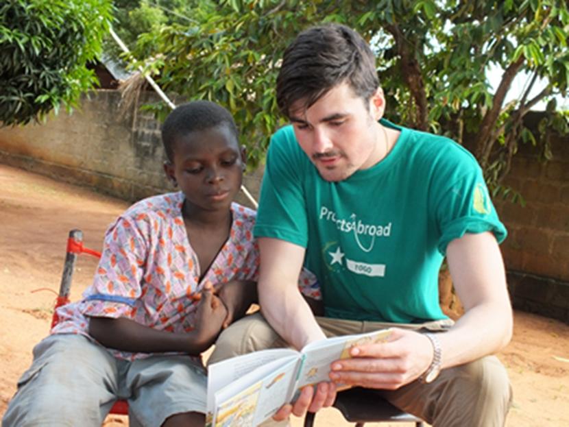 Un volontaire de Projects Abroad fait de la lecture avec un jeune garçon dans le cadre de la mission d’aide à l’enfance au Togo