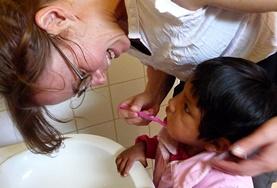 Care A volunteer on the Care Project in Bolivia teaches a young child about the importance of hygiene and brushing teeth.