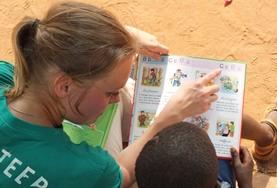 Togo A High School Special volunteer reads to a young boy in Togo during her Care & Community with French Project.